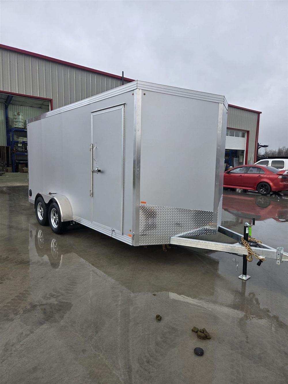 Silver enclosed trailer with tandem axles and side entry door
